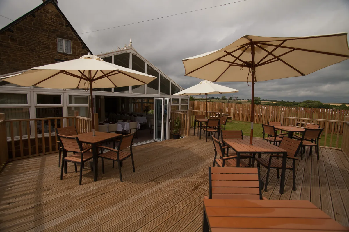 Outdoor decking terrace with tables, seating and views across The Indian Queen garden