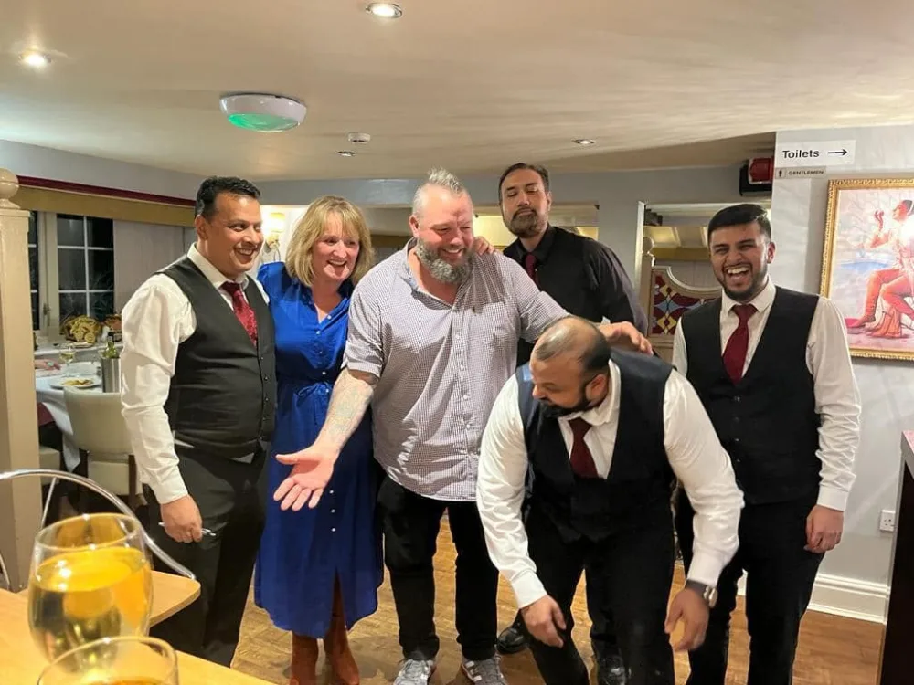 Diners and smartly dressed restaurant staff celebrating together at The Indian Queen