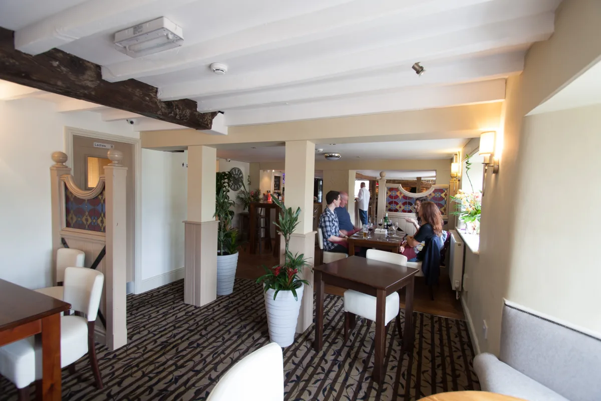 The Indian Queen dining room with guests, white chairs and exposed timber beams